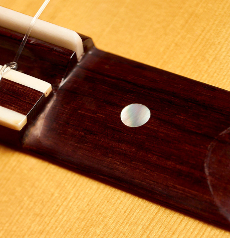 The bridge ornament, saddle any nylon strings of a 2015 Manuel Adalid "Torres" classical guitar made of spruce and Indian rosewood