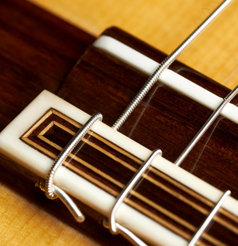 The bridge, tie-block and saddle of a 2023 Colin van Aelbrouck flamenco guitar made of spruce and cypress