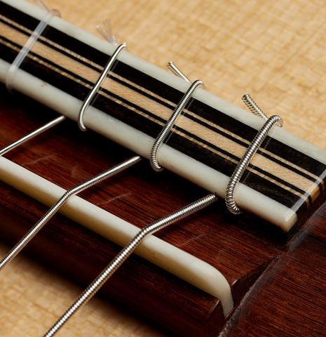 The bridge, tie-block and saddle of a 2025 Colin van Aelbrouck classical guitar made of spruce and African rosewood