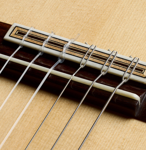 The bridge, tie-block and saddle of a 2025 Colin van Aelbrouck "Rodriguez" classical guitar made of spruce and maple