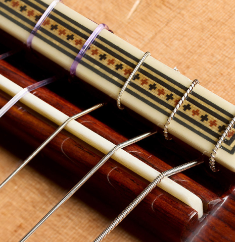 The bridge, tie-block and saddle of a 2021 Alhambra “Mengual y Margarit NT” classical guitar made of cedar and Indian rosewood