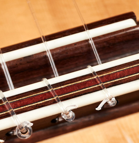 The bridge, saddle, and tie block of a 2002 Simon Ambridge classical guitar made with spruce and CSA rosewood.