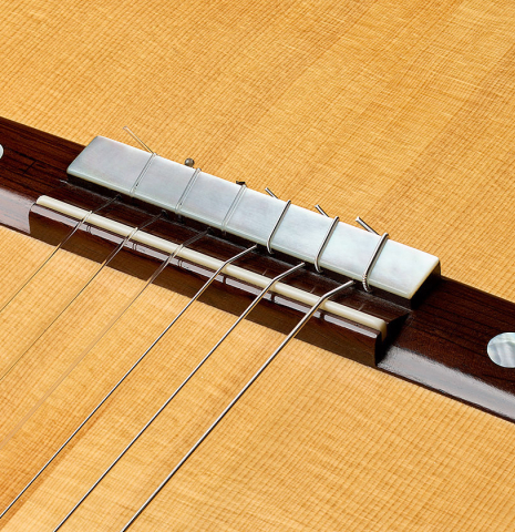 The bridge, tie-block and saddle of a 2008 Simon Ambridge "1887 Torres SE 111" classical guitar made of spruce and maple