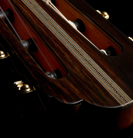 The headstock veneer and slots of a 2026 Ariel Ameijenda "70th Anniversary" classical guitar made of alerce and CSA rosewood