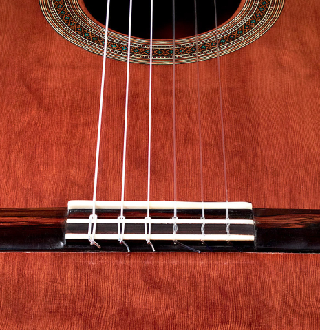 This is a close-up shot of the bridge, tie-block and saddle of a 2022 Ariel Ameijenda "Confessional" AL/BL classical guitar