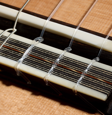 The bridge, tie-block and saddle of a 2025 Ariel Ameijenda "70th Anniversary - Lightning Strikes" classical guitar made of cedar and CSA rosewood