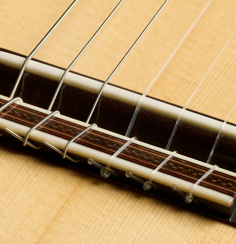 The bridge, tie-block and saddle of a 2026 Mario Aracama classical guitar made of spruce and African rosewood