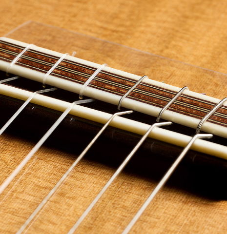 The bridge, tie-block and saddle of a 2025 Mario Aracama classical guitar made of cedar and cocobolo