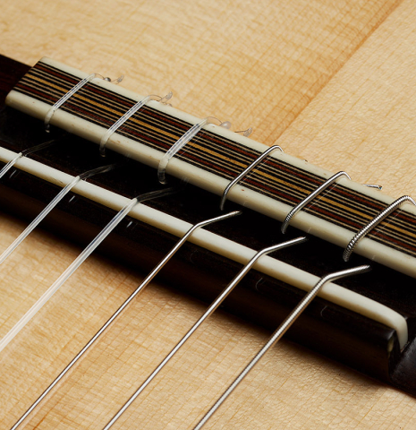 The bridge, tie-block and saddle of a 2025 Mario Aracama classical guitar made of spruce and Indian rosewood