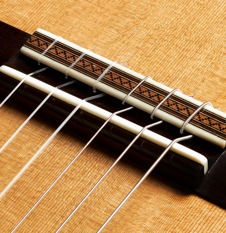 The bridge, tie-block and saddle of a 2024 Mario Aracama classical guitar made of cedar and Kamagong
