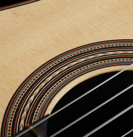 The soundboard and rosette of a 2021 Kevin Aram "Carmen 640" classical guitar made of spruce and Indian rosewood