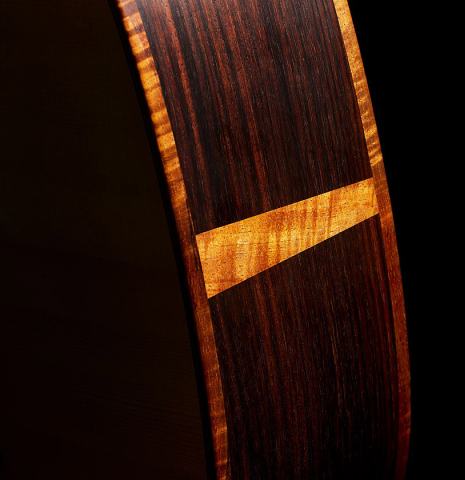 The sides at the foot of a 2021 Kevin Aram "Carmen 640" classical guitar made of spruce and Indian rosewood