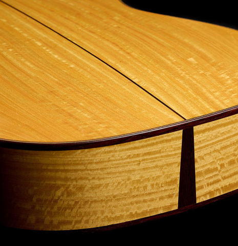 The back and sides at the foot of a 2021 Kevin Aram "Nancy" classical guitar made of spruce and satinwood