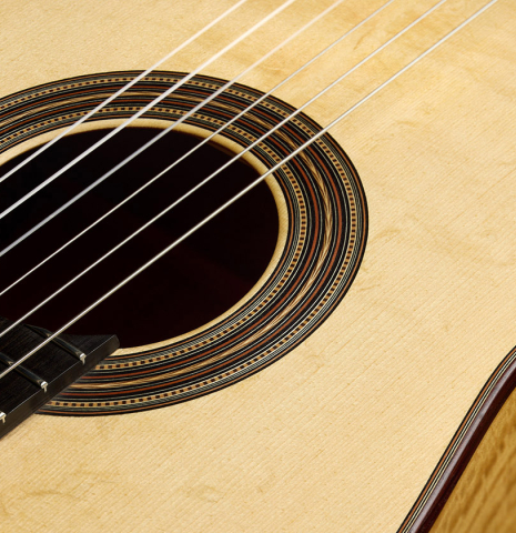 The soundboard and rosette of a 2021 Kevin Aram "Nancy" classical guitar made of spruce and satinwood