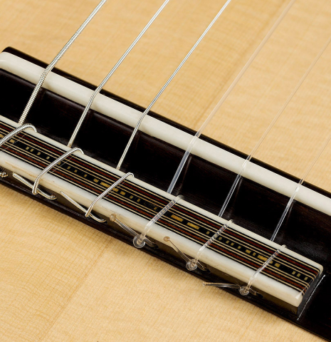 The bridge, tie-block and saddle of a 2025 Mario Aracama classical guitar made of spruce and Tamarind