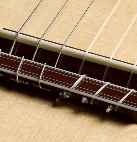 The bridge, tie-block and saddle of a 2025 Manuel Arango classical guitar made of spruce and Indian rosewood