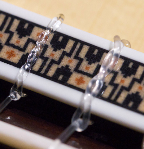 The ornamented bridge of an Asturias "Custom S" classical guitar made of spruce and Indian rosewood