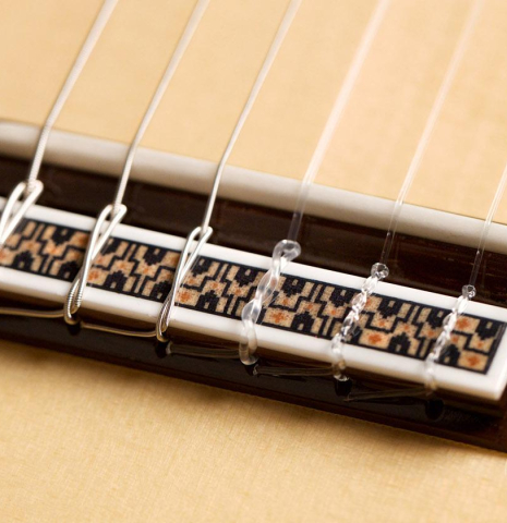 The bridge and saddle of a 2022 Asturias "Custom S" classical guitar made of spruce and Indian rosewood with a 630 mm scale.