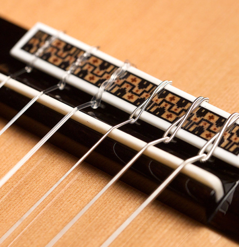 The bridge, saddle and nylon strings of a 2022 Asturias "Custom C" classical guitar made with 630 mm scale