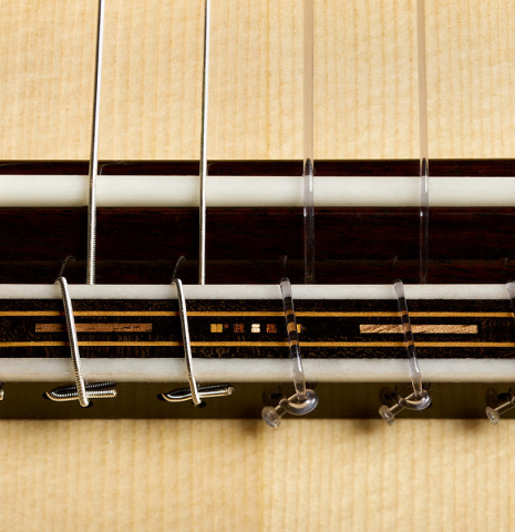 The bridge, tie-block and saddle of a 2026 Francesco Baccaglion classical guitar made of spruce and Indian rosewood