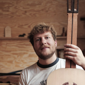 Henrik Ballowitz in his workshop, holding an unfinished classical guitar