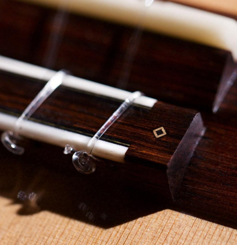 The bridge and saddle of a 2020 Kris Barnett classical guitar made with cedar and African rosewood