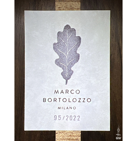 The label with a painted leaf of a 2022 Marco Bortolozzo classical guitar made with spruce and exotic ebony