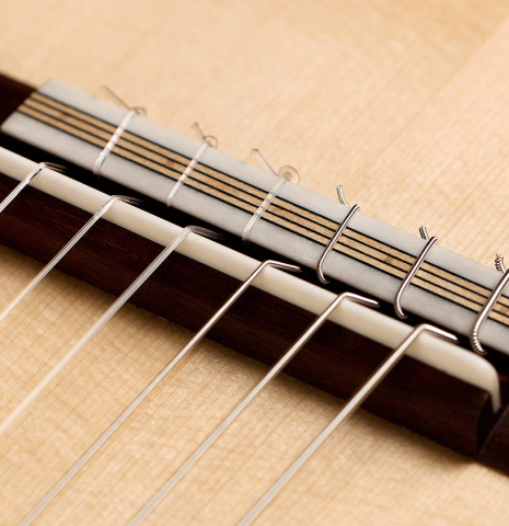 The bridge and saddle of a 2022 Marco Bortolozzo classical guitar made with spruce and exotic ebony