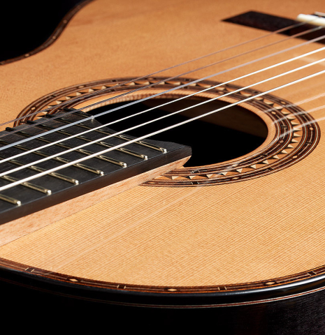 The elevated fingerboard and top of a 2025 Kris Barnett classical guitar made of cedar and exotic ebony