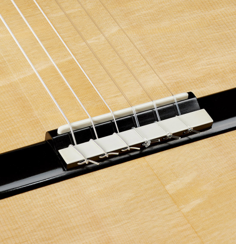 The bridge, tie-block and saddle of a 2025 Marco Bortolozzo classical guitar made of spruce and pomellè mahogany