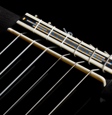 The bridge, tie-block and saddle of a 2026 Marco Bortolozzo "Gold Record - REG Limited Edition" classical guitar made of spruce and satinwood