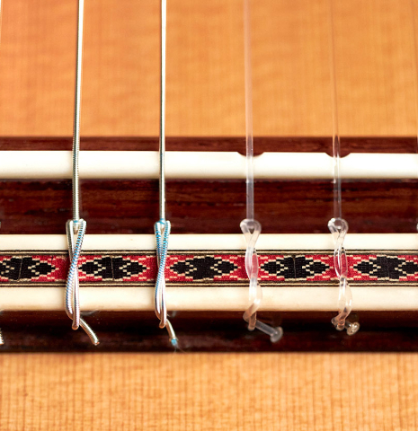 The bridge, saddle and nylon strings of a 2022 Michel Belair &quot;Hommage a Daniel Friederich&quot; classical guitar made of cedar and Indian rosewood