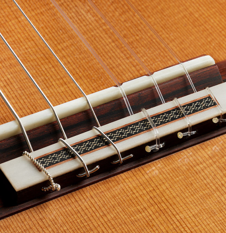 The bridge, tie-block and saddle of a 2025 Michel Belair "Double Top" classical guitar made of cedar and Indian rosewood