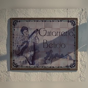 Hand-painted tile sign reading Guitarrería Bellido on the wall outside the Bellido workshop in Granada