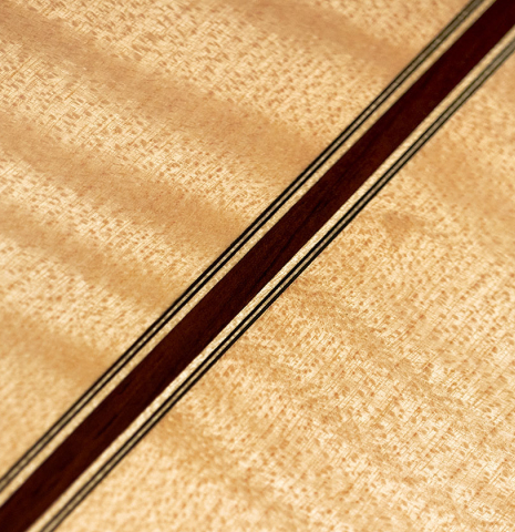 Detail of the back and center seam of a 2023 Tobias Berg classical guitar made of spruce and flamed maple.