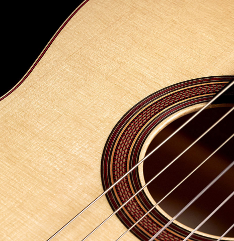 Closeup detail of rosette and top of a 2023 Tobias Berg classical guitar made of spruce and flamed maple.