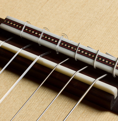 The bridge, tie-block and saddle of a 2026 Martin Blackwell "640" double-top classical guitar made of spruce and Indian rosewood