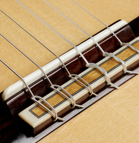 The bridge, tie-block and saddle of a 2024 Eduardo Bossa classical guitar made of spruce and Indian rosewood