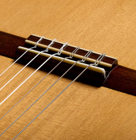 The bridge, tie-block and saddle of a 2026 Eduardo Bossa classical guitar made of cedar and ovangkol