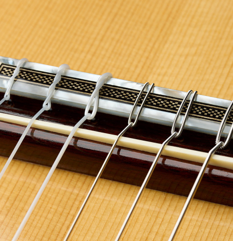 The bridge, tie-block and saddle of a 2026 Eduardo Bossa classical guitar made of spruce and comino crespo