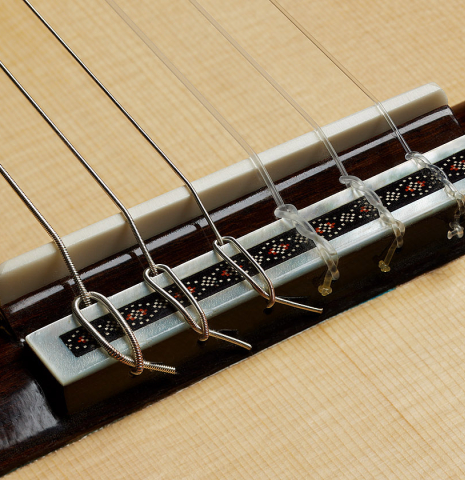 The bridge, tie-block and saddle of a 2025 Kenneth Brogger "Mosaic" classical guitar made of spruce and Indian rosewood