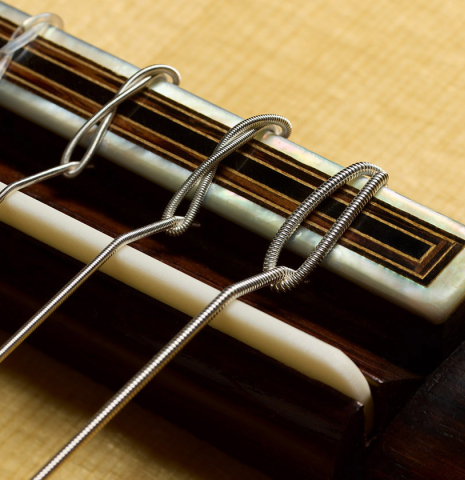 The bridge, tie-block and saddle of a 2025 Ivan Bruna classical guitar made of spruce and Indian rosewood