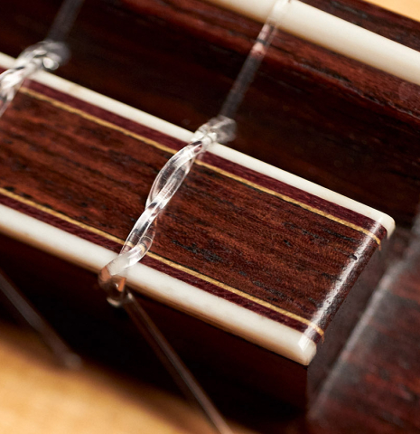 This is a close-up of the bridge, tie-block and saddle of a 1986 Cynthia H. Burton SP/MH classical guitar