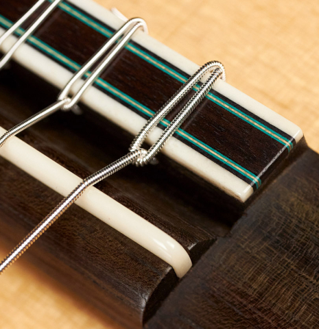 A close-up of the bridge of a 2012 Geza Burghardt &quot;1943 Hauser&quot; classical guitar made with spruce and maple.