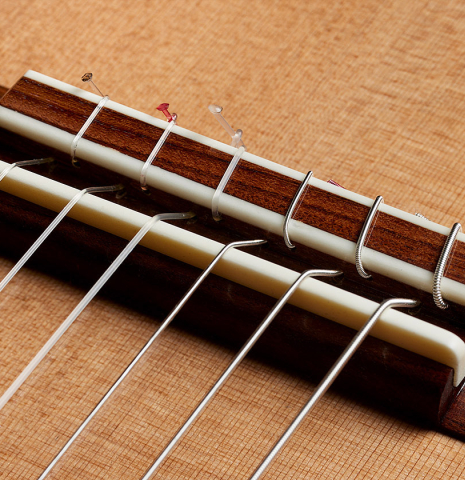 The bridge, tie-block and saddle of a 2025 Carlos Juan Busquiel classical guitar made with cedar and African rosewood