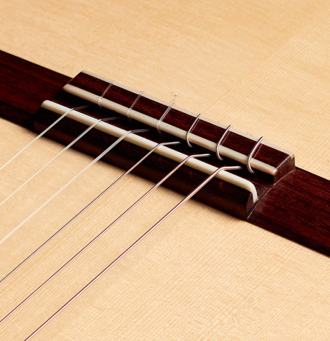 The bridge of a 2022 Carlos Juan Busquiel classical guitar made with spruce and CSA rosewood.