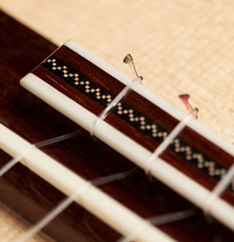 The bridge, tie-block and saddle of a 2023 Carlos Juan Busquiel classical guitar made with spruce and CSA rosewood.