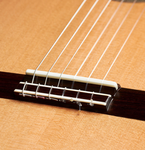 The bridge, tie-block and saddle of a 2024 Carlos Juan Busquiel classical guitar made with cedar and CSA rosewood