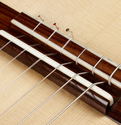 The bridge, tie-block and saddle of a 2024 Carlos Juan Busquiel classical guitar made with spruce and African rosewood