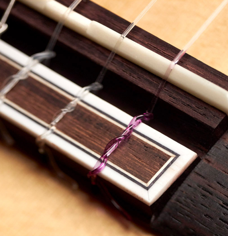 The bridge and tie block of a 2023 Hermanos Camps "CL20-S" classical guitar made of spruce and exotic ebony.